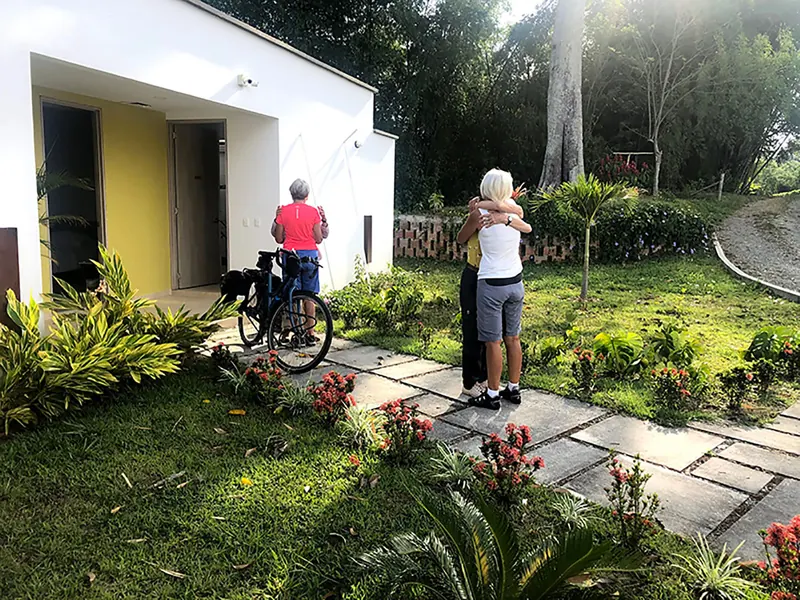 Two cyclists saying goodbye in front of the house, with their bikes