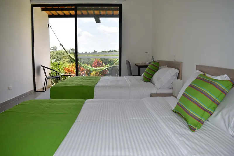Habitación con dos camas dobles y la terraza al fondo
