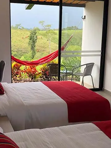 Habitación con dos camas dobles y la puerta abierta a la terraza